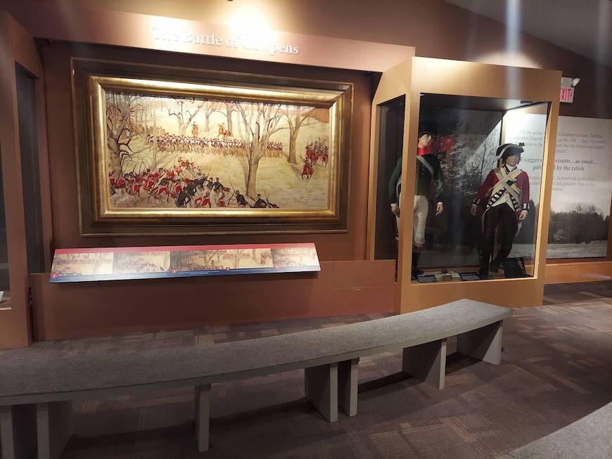 Inside the Cowpens National Battlefield visitor center museum. There is artwork depicting the battle between the patriots and British. There are also mannequins wearing soldier uniforms from the time.