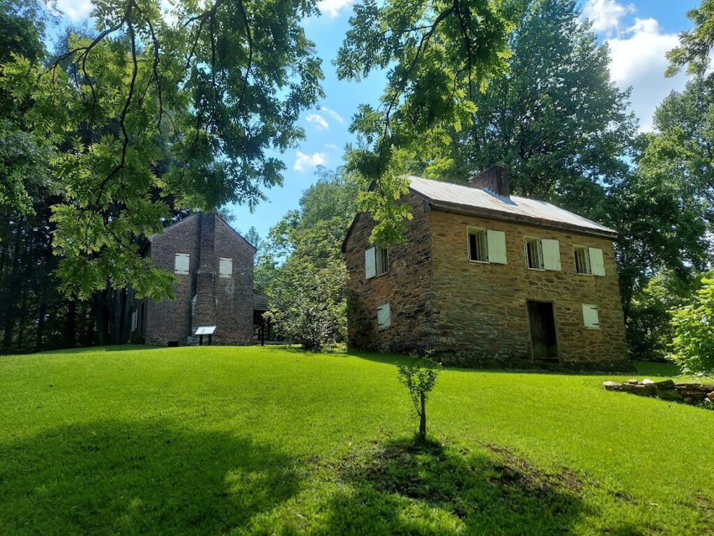 There are two old houses. On the right is a beige stone brick house built in 1792, and on the left is the two-story red brick William Richards house.