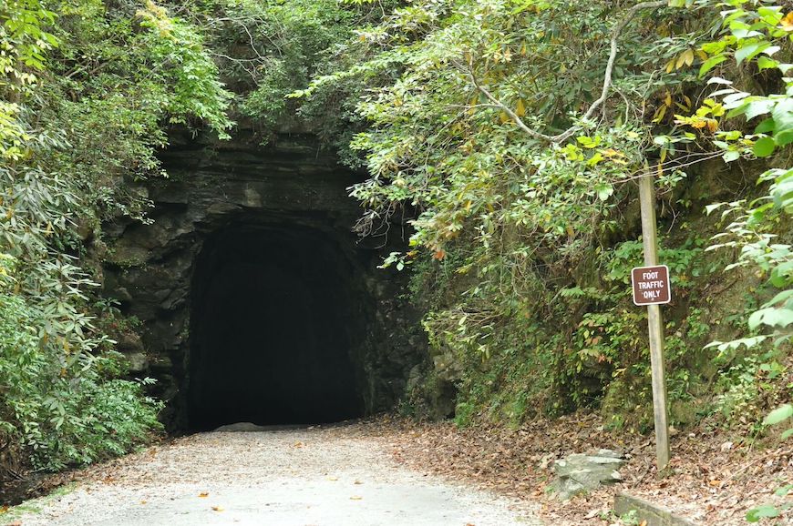 Dark entrance of Stumphouse Tunnel. There is a sign that says foot traffic only.